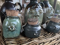 a group of jugs with faces on them on a wicker basket